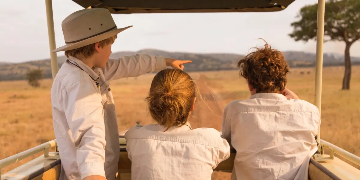 Kori guide pointing out wildlife to guests from a safari vehicle